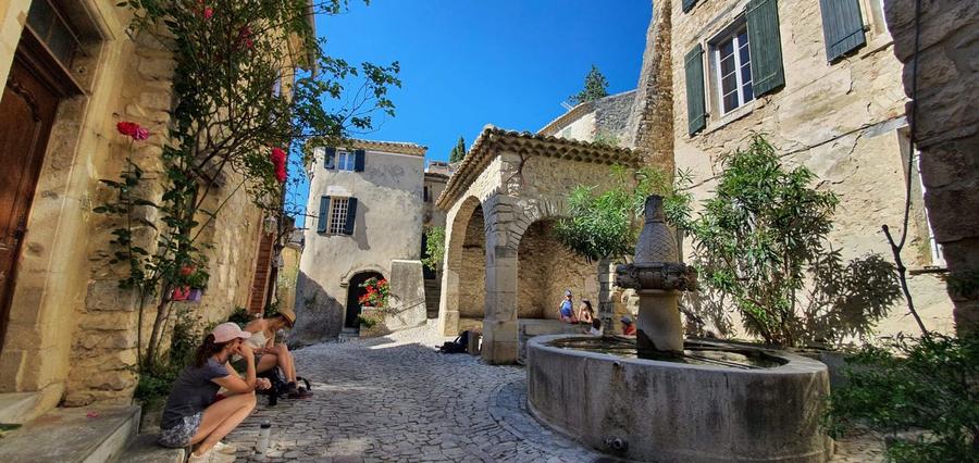 Une ruelle pavée et sa fontaine, dans un village perché