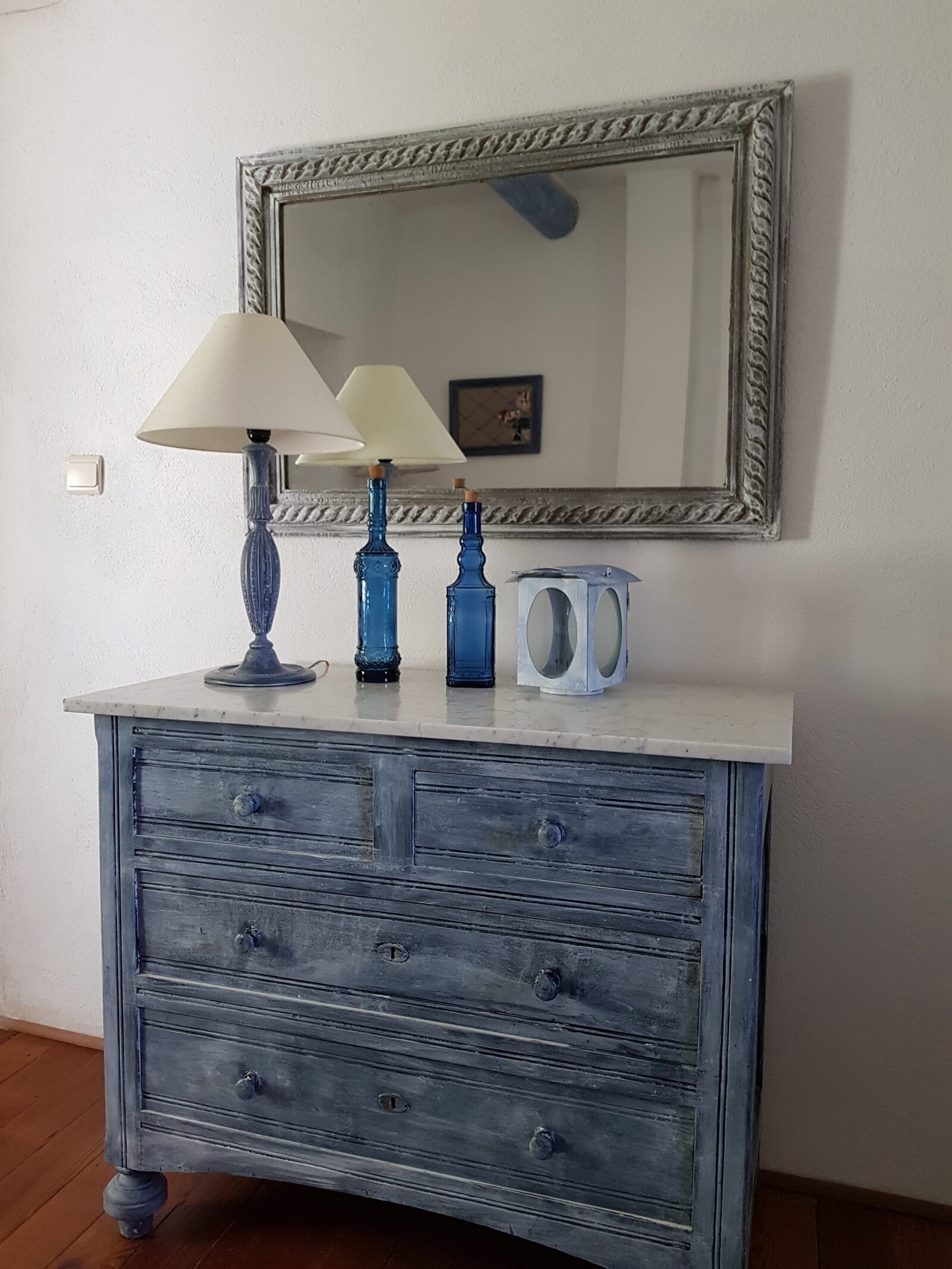 Commode patinée bleue et miroir en bois sculpté dans une chambre