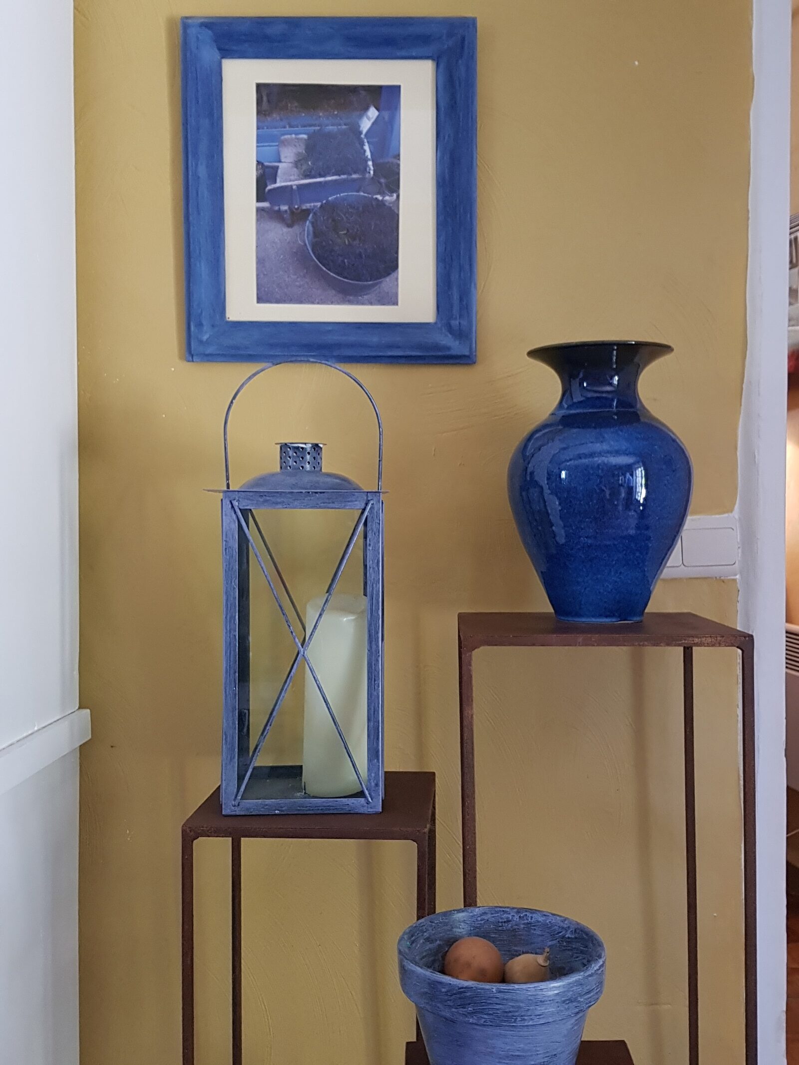 Coin déco avec lanterne et vase en céramique bleue sur fond ocre
